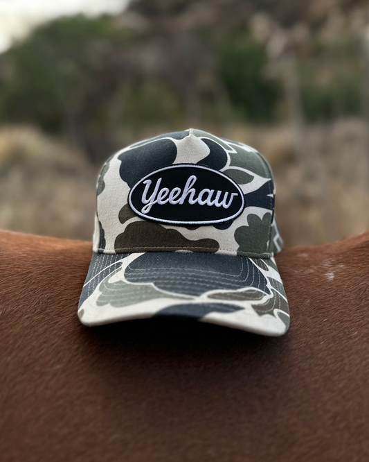 Camouflage-patterned cap with 'Yeehaw' text on a horse's back against a mountainous background